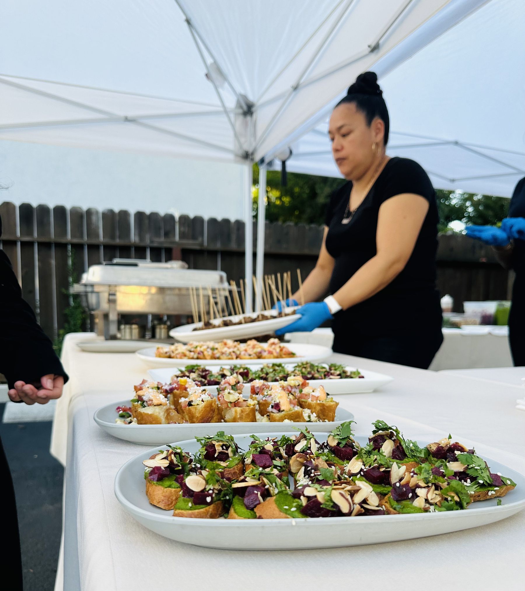 Kina plating fresh appetizers for a backyard catering event